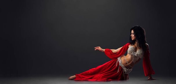 Woman in red arabic dress dancing oriental dances in stalls - Fotografie, Obrázek