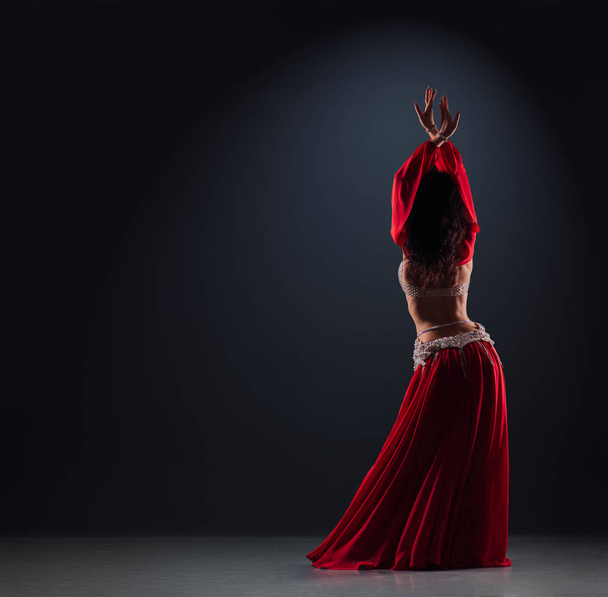 schöne schwarzhaarige Mädchen in einem roten ethnischen Kleid auf der Bühne tanzen - Foto, Bild