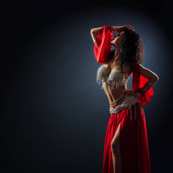 beautiful black-haired girl in red ethnic dress dancing oriental - 写真・画像