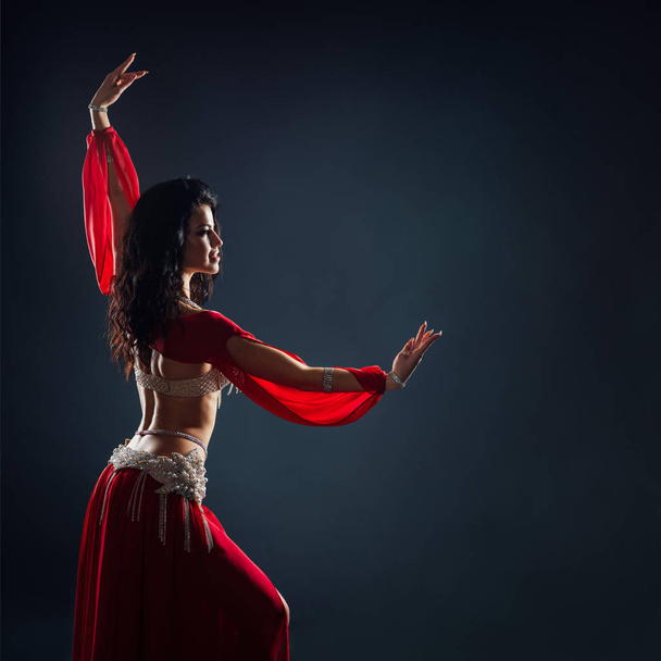 beautiful black-haired girl in red ethnic dress dancing oriental - Фото, изображение