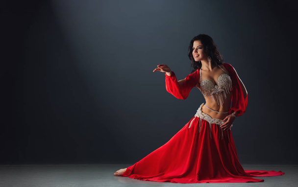 Woman in red arabic dress dancing oriental dances in stalls - Foto, immagini