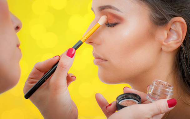 Makeup professional artist applying eyeshadow on woman model - Foto, afbeelding