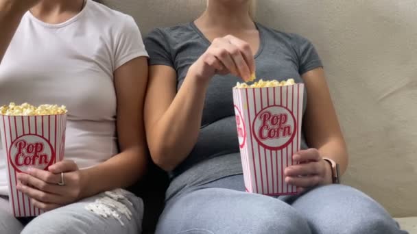 Happy family mom with kid daughter watching tv together with popcorn - Video
