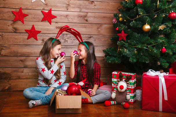 Two happy funny little sisters having fun near Christmas tree at home - Foto, Imagem