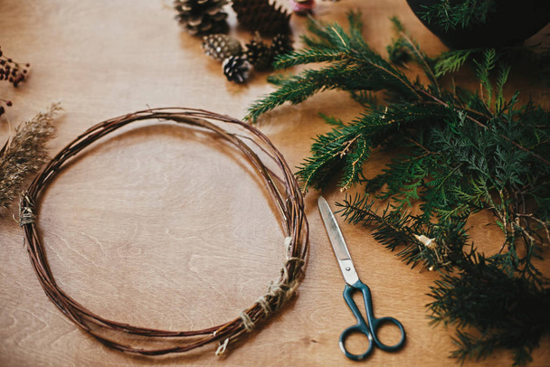 Making christmas wreath.Fir branches, pine cones, thread, scisso - Foto, imagen