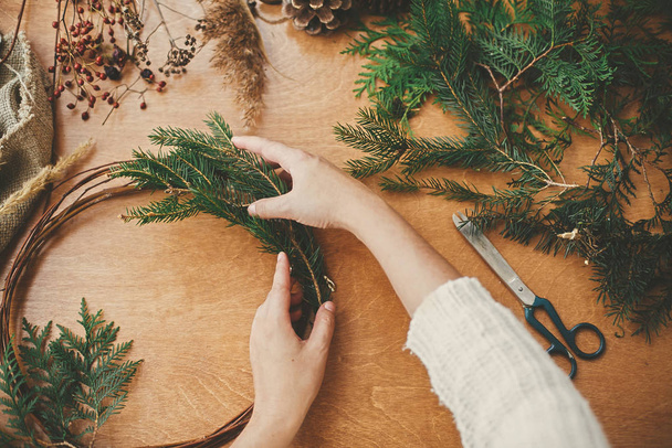 素朴なクリスマスリースフラットレイアウトを作る。モミの枝を持つ手 - 写真・画像