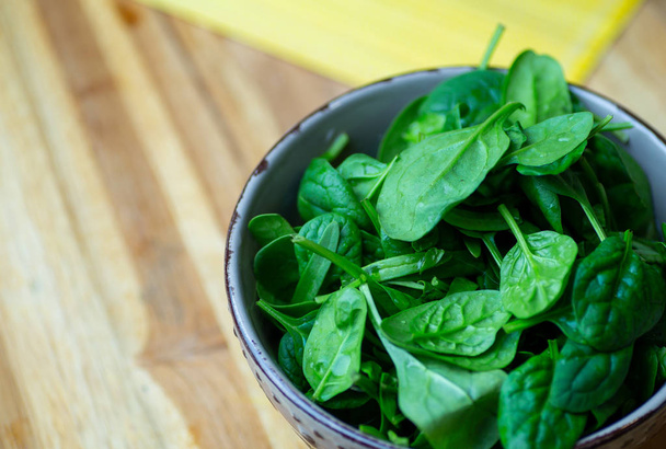 Fresh spinach leaves in a bowl on a wooden table. Eco vegan spin - Foto, imagen