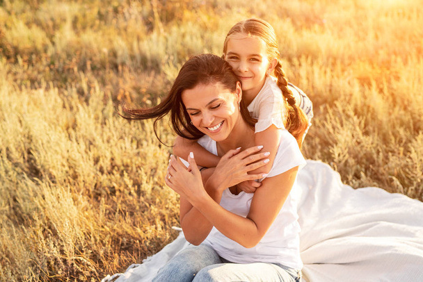 Daughter hugging mother on rural sunny field - Foto, immagini