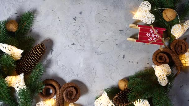 Regalo de Navidad se lanza a otros juguetes navideños. Cerca hay ramas de pino y abeto, trineos pequeños, conos y nueces. Regalos para el Año Nuevo. Feliz Navidad y feliz celebración. Vista superior
 - Imágenes, Vídeo