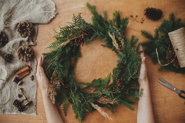 Rustic Christmas wreath, flat lay. Hands holding christmas wreat - Valokuva, kuva