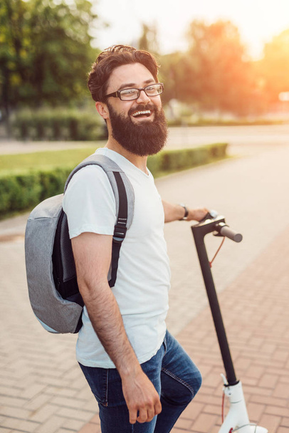 Happy urban guy with scooter in park - Фото, изображение