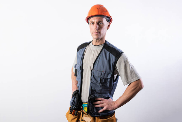 legte der Baumeister die Hände auf die Hüften. in Arbeitskleidung und Hut. - Foto, Bild