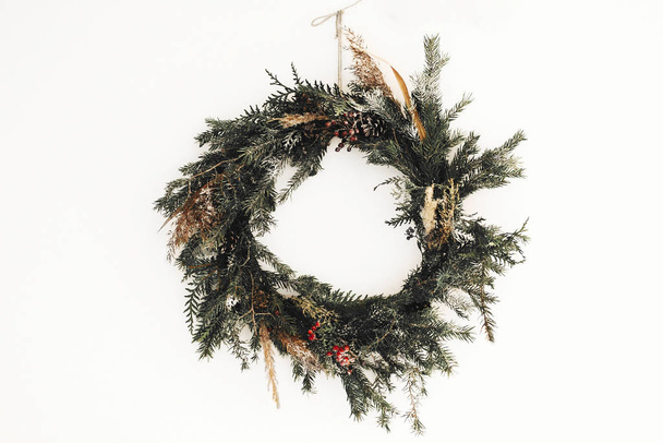 Corona rústica de Navidad hecha de ramas de pino, conos y bayas
 - Foto, Imagen