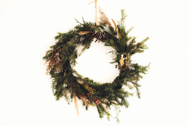 Corona rústica de Navidad hecha de ramas de pino, conos y bayas
 - Foto, Imagen