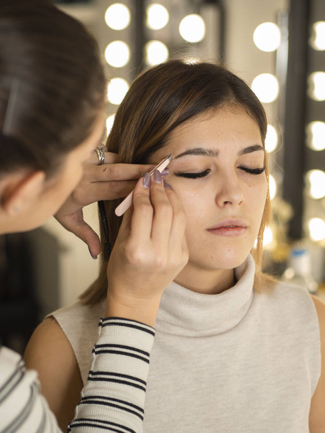 Kosmetikerin macht Microblading Augenbrauen für ein junges Mädchen. getönte Augenbrauen mit semi-permanentem Make-up - Foto, Bild