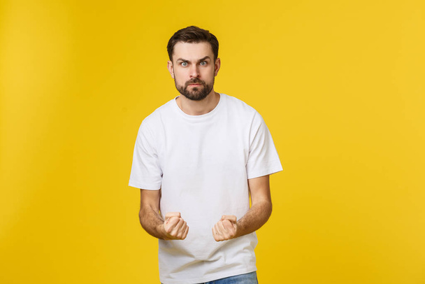 Portrait unhappy handsome man looking at camera on yellow background. - Photo, Image