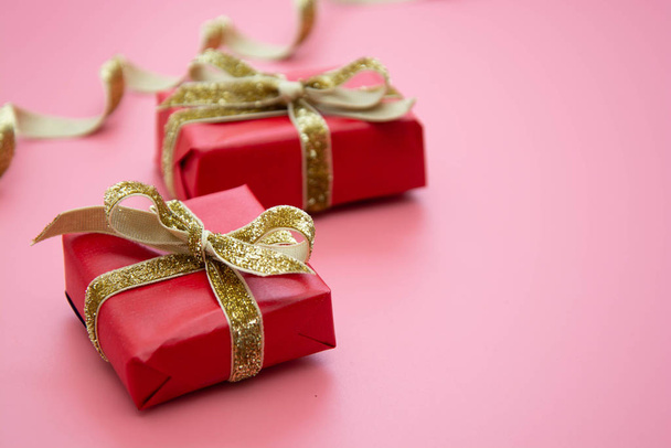 Red gift box and golden bow, on pink background. Valentine's Day, Birthday, Party concept. - Valokuva, kuva