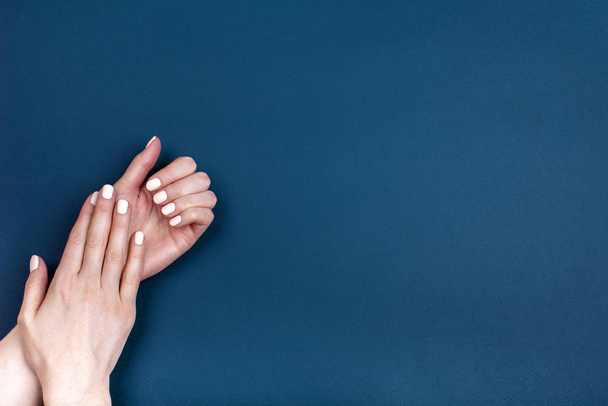 Красивые женские руки с классическим маникюром на синем фоне
. - Фото, изображение
