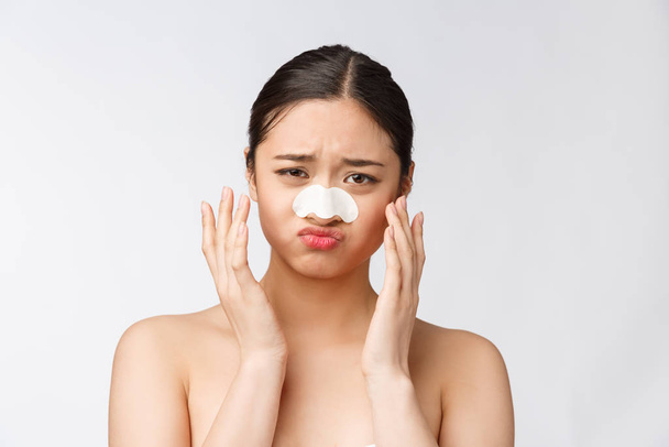 Kosmetologia. Portret pięknej modelki azjatyckiej z maską na nosie. zbliżenie zdrowej młodej kobiety z czystej miękkiej skóry i świeżego naturalnego makijażu. - Zdjęcie, obraz