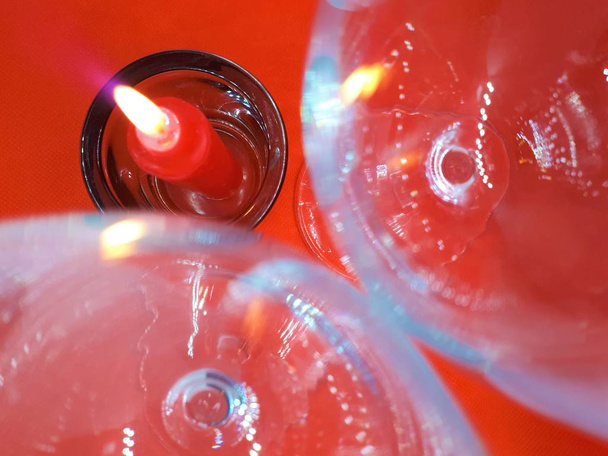  bokeh hatás, üveg / kristály szemüveg és egy gyertyatartó egy piros gyertya egy piros elvont háttér - Fotó, kép