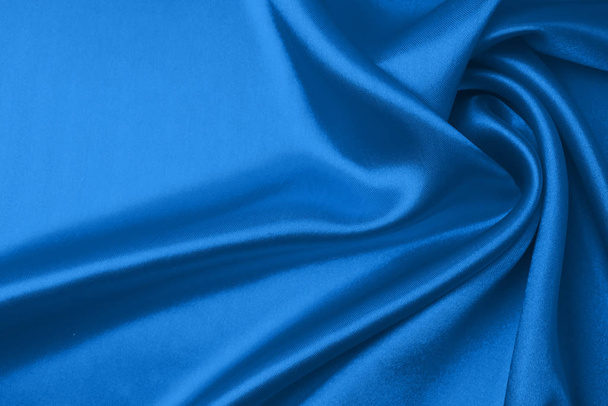 Textile and texture concept of trendy classic blue color in 2020 year. Sample of wavy silk fabric of classic blue color - closeup. - 写真・画像