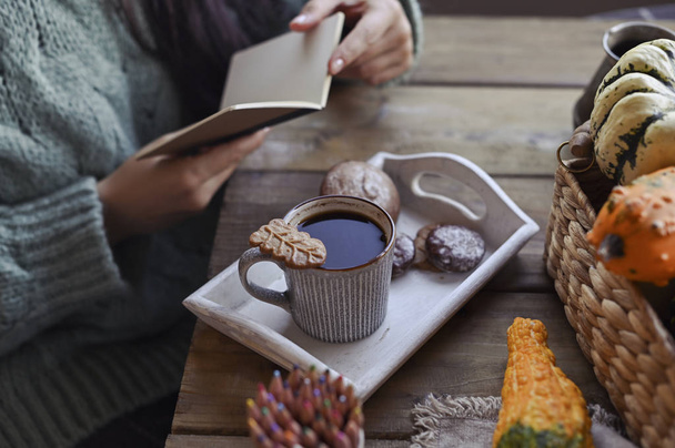 Autumn concept, pumpkins, hot steaming cup of coffee on a wooden table background. Seasonal, morning coffee with biscuit cinnamon cookies, Sunday relaxing. Girl in a frame with a notebook. - Fotografie, Obrázek