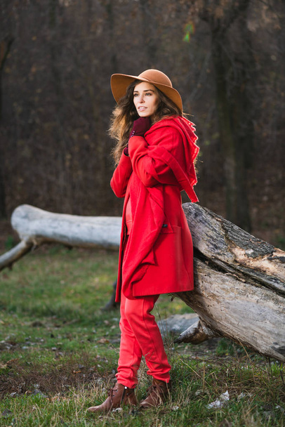 Menina em vermelho casual perto de árvore log
 - Foto, Imagem