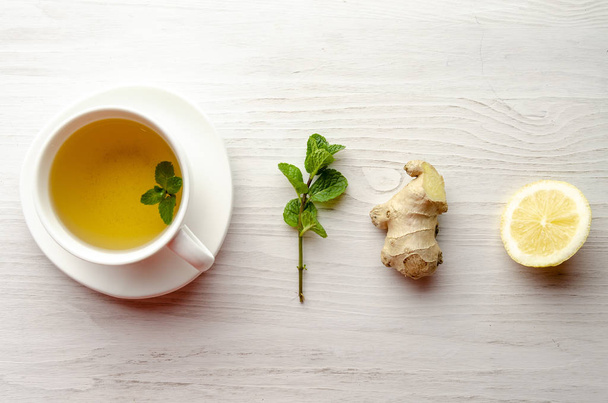 Cup and teapot of herbal tea with fresh mint on wooden boards - Фото, изображение