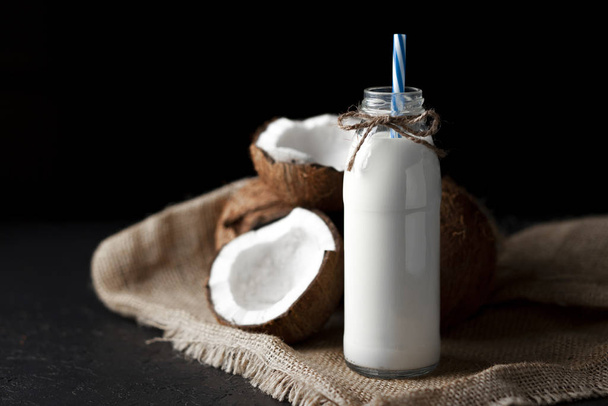 свежее кокосовое молоко в бутылке на темном фоне, кокосовый коктейль на черном столе
 - Фото, изображение
