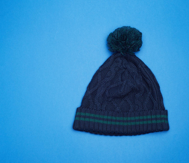 sombrero de punto azul oscuro con pompón sobre fondo azul
 - Foto, imagen