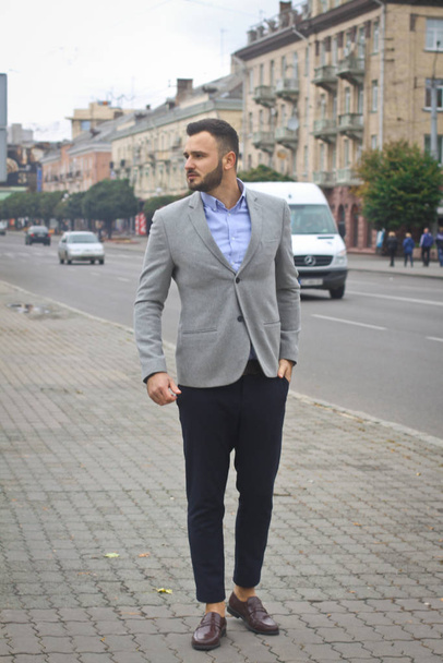 Portrait of a businessman on the street near the road of a European city. A bearded handsome man dressed stylishly. Fashionable guy hipster. Stock photos - Zdjęcie, obraz