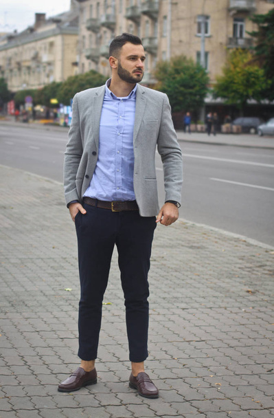 Portrait of a businessman on the street near the road of a European city. A bearded handsome man dressed stylishly. Fashionable guy hipster. Stock photos - 写真・画像