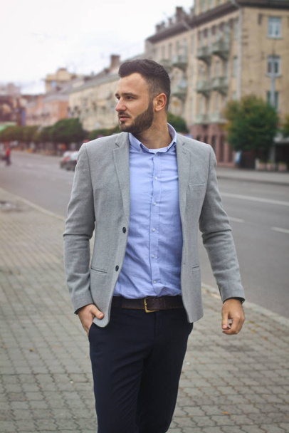 Portrait of a businessman on the street near the road of a European city. A bearded handsome man dressed stylishly. Fashionable guy hipster. Stock photos - Zdjęcie, obraz