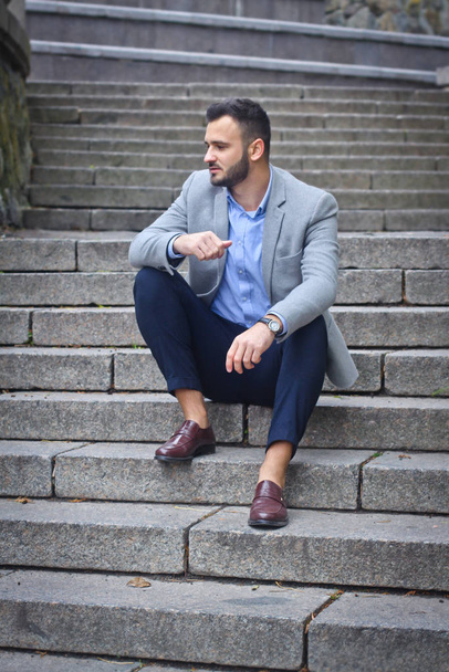 Portrait of a bearded man near the big steps of an old European castle. Businessman thinking over a future project. Fashionable guy with stylish clothes. - Фото, зображення