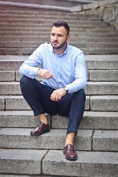 Portrait of a bearded man near the big steps of an old European castle. Businessman thinking over a future project. Fashionable guy with stylish clothes. - Fotó, kép