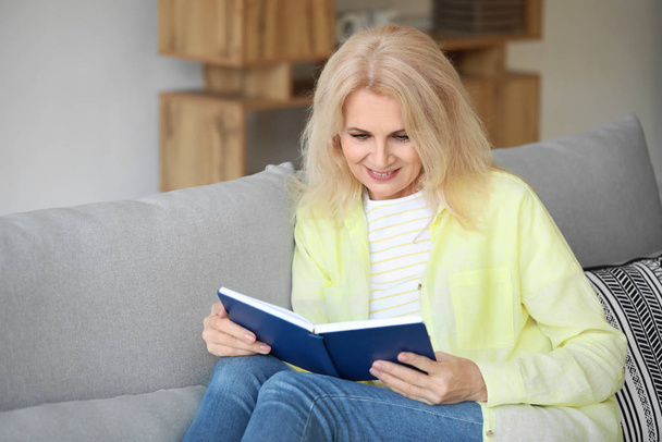Bella donna matura lettura libro a casa - Foto, immagini
