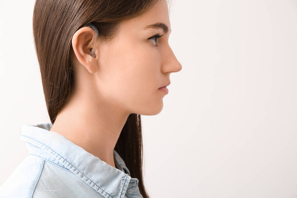 薄明かりの中で補聴器を持つ若い女性 - 写真・画像