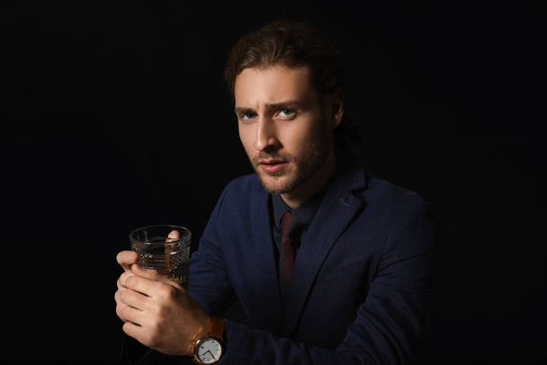Portrait d'un bel homme d'affaires avec un verre d'alcool sur fond sombre
 - Photo, image