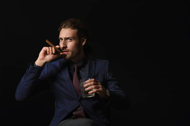 Portrait of handsome businessman with alcohol and cigar on dark background - Fotoğraf, Görsel