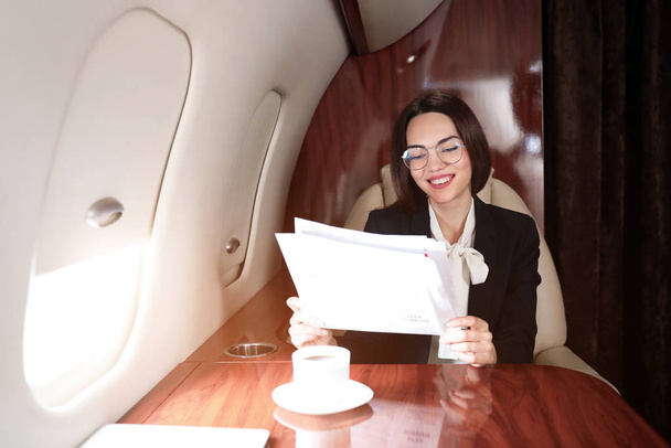 Üzletasszony újságot olvas a modern magánrepülőgép fedélzetén. - Fotó, kép