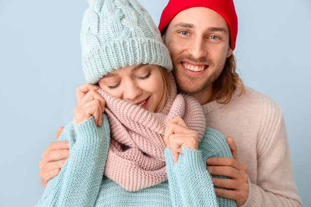 Happy couple in winter clothes on color background - Fotó, kép