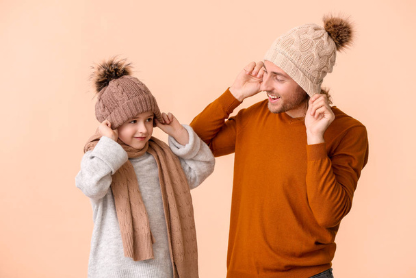 Man and his son in winter clothes on color background - Fotoğraf, Görsel