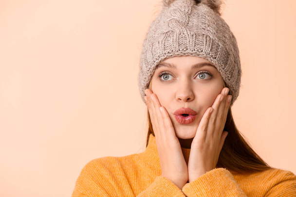 Beautiful surprised woman in winter clothes on color background - Fotoğraf, Görsel
