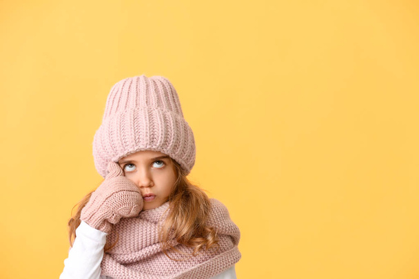 nachdenkliches kleines Mädchen in Winterkleidung auf farbigem Hintergrund - Foto, Bild