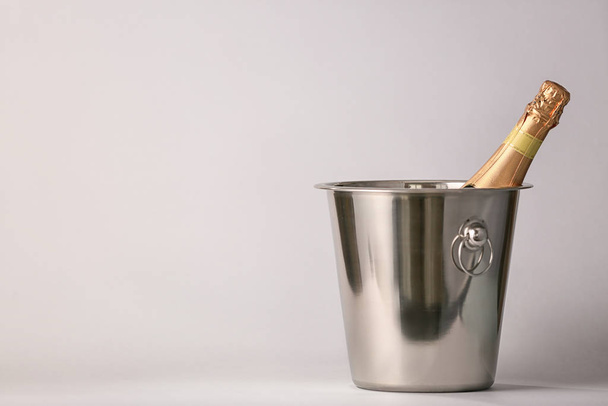 Bucket with bottle of champagne on light background - Photo, Image