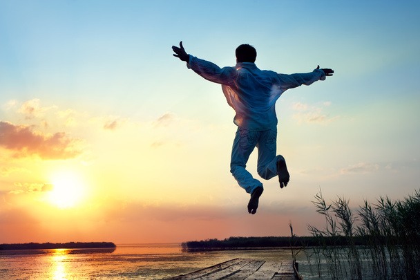 Man jumping in sea sunset - Φωτογραφία, εικόνα