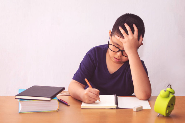 Набридлий і втомлений азіатський студент робить домашнє завдання
  - Фото, зображення