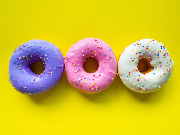 Donutlar çeşitli renklerde turuncu beyaz pembe, yüksek enerji gıdaları ve sağlıklı oranlar, tatlı aromalı şekerler, eşleştirme arka planı - Fotoğraf, Görsel