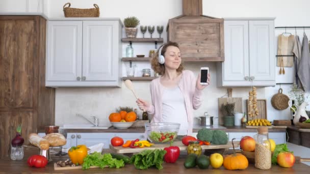 Happy Lifestyle, Pregnancy And Technology Concept. Cheerful Pregnant Girl Dancing On Kitchen With Cell Phone In Hands. - Filmagem, Vídeo
