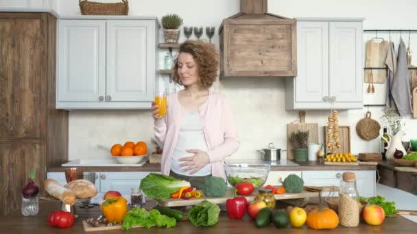 Young Pregnant Woman With Glass Of Orange Juice In The Kitchen - Materiał filmowy, wideo